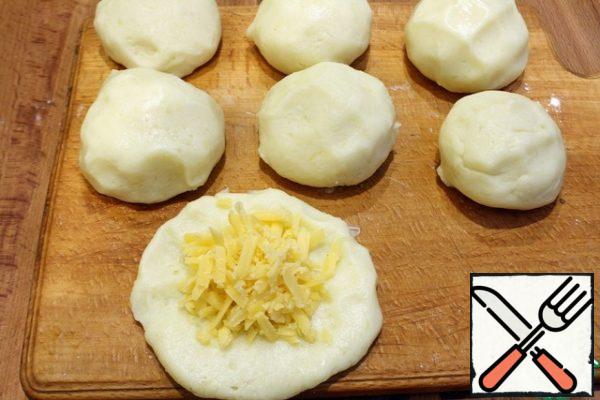 Cheese RUB on a large grater, hands moisten with vegetable oil, form small balls with a diameter of five centimeters, flatten into a flat cake, put the grated cheese and again form balls, but with a filling.