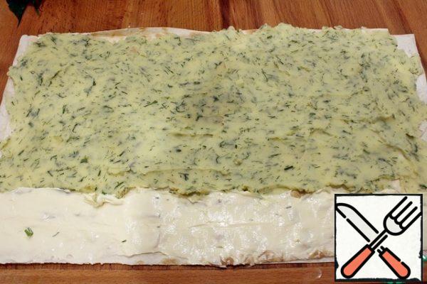 From above, put the second sheet of pita bread, spread the puree, smear not reaching the edge of five centimeters. On these five centimeters, apply the remaining cheese for gluing the roll.