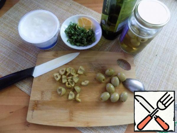 While the potatoes are cooking, cut the olives. If they are small, they can be cut in half. I cut it into quarters. Wash the parsley, dry with a paper towel, cut off the stalks and cut not very finely.