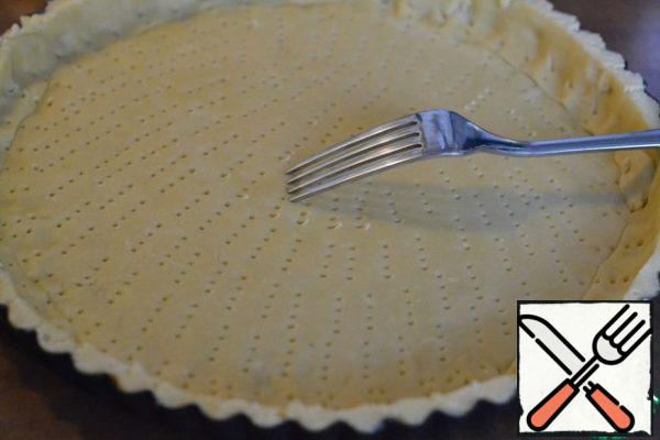 Grease the baking dish with oil.
Put the dough into a mold, forming high sides.
Pierce the dough with a fork.
