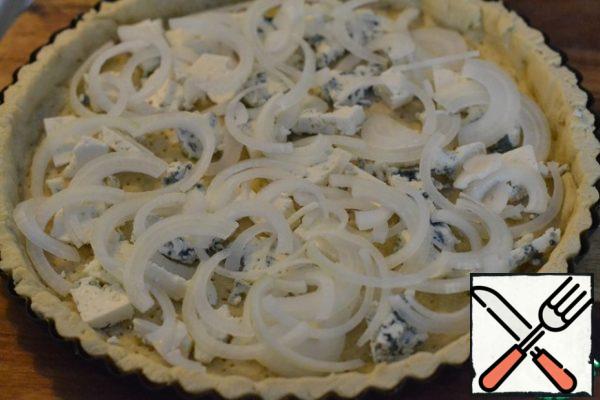 Cut the cheese with blue mold arbitrarily and put it on a hot base for a custard pie.
Cut the onion into half rings. Spread on cheese.
