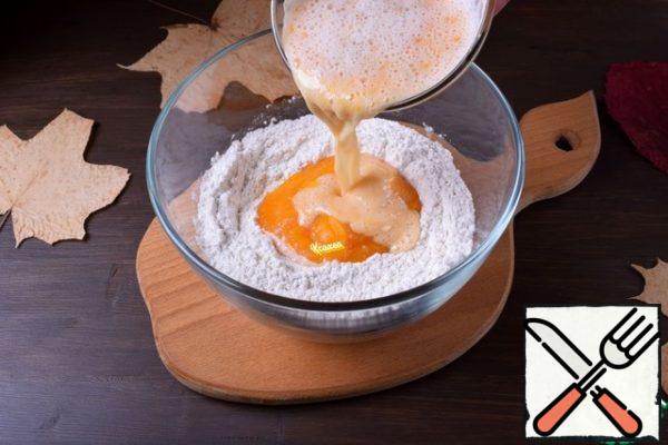 In the flour mixture, add pumpkin puree, yolk and prepared yeast.