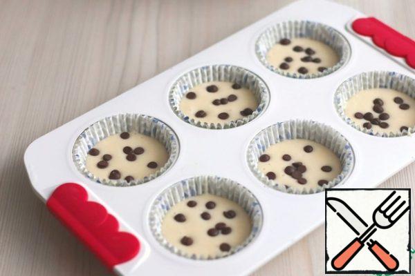 In a baking dish, put paper capsules. In capsules add batter (2/3 parts). Top with chocolate drops.
To send the form in a preheated t180-190S the oven.