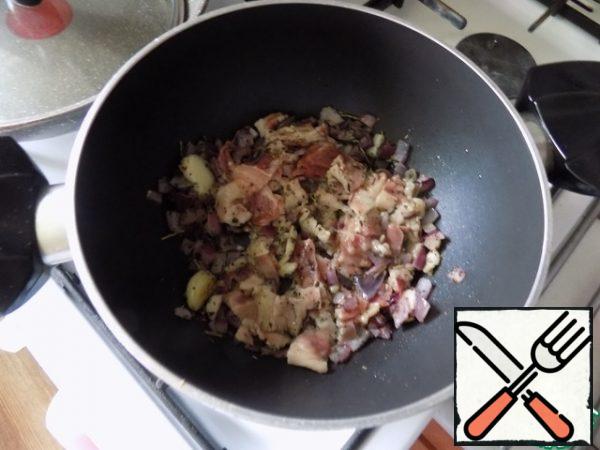 Since we have a recipe of Italian cuisine, we take olive oil for its preparation and will not replace it with any other! To make this soup, I will take a thick-bottomed pot in which I will fry the vegetables and bacon and then cook the minestrone. Pour 1 tbsp oil, heat it and spread the crushed garlic. Fry it for a minute, it will give its flavor to the oil. It can be removed. Next-chopped onion, fry until soft, add spices: Basil, thyme, rosemary. You can take a ready-made set of Italian herbs. Spread the chopped bacon. Fry quite a bit.