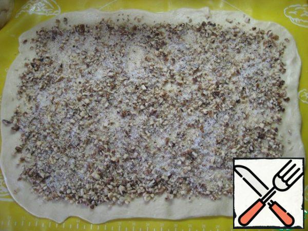 Sprinkle the layer of dough evenly over the entire surface of the sugar-nut filling, leaving small clean edges. Roll the filling with a rolling pin, slightly pressing.