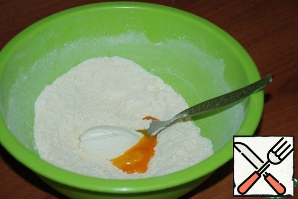 In the flour mixture, put the yolk of one egg (the protein will be added to the curd layer), sour cream and sliced butter.