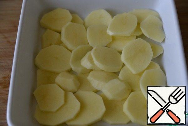 Peel the potatoes and cut them into thin slices so that they have time to cook.
We take the mold, lubricate it with oil, spread the potatoes.
