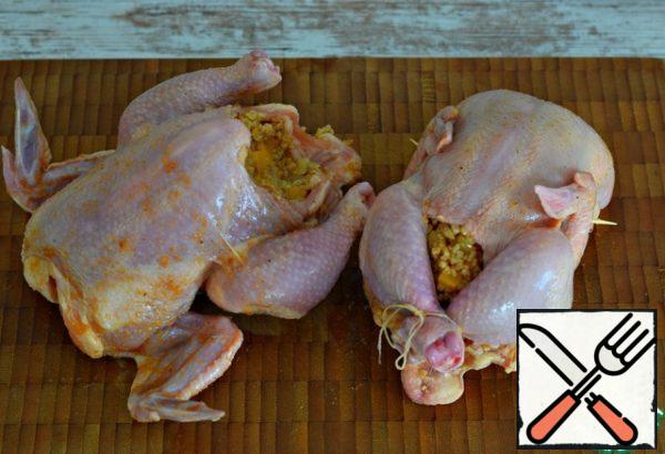 Stuff the chicken with wheat and vegetable filling.
Tie the chicken legs with a culinary thread, pin the wings with toothpicks. Thus, the chickens will not "open up" during cooking and the filling will not fall out.
