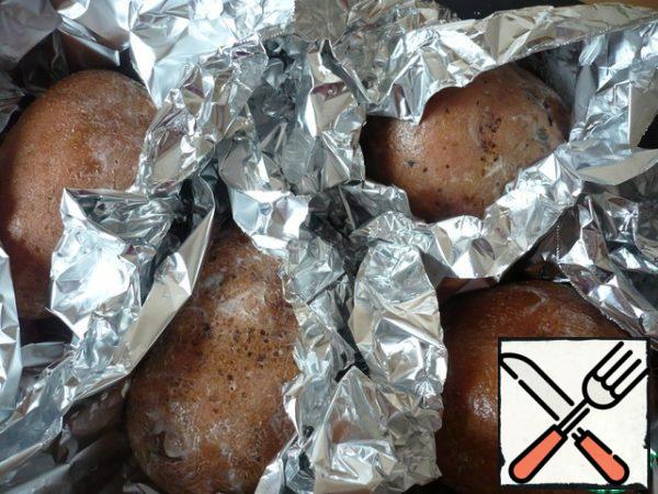 Prick the potatoes with a fork on all sides and brush with 1 tbsp melted butter. Bake the potatoes in the oven on a baking sheet at 200 degrees for about 1 hour until tender and desired softness.