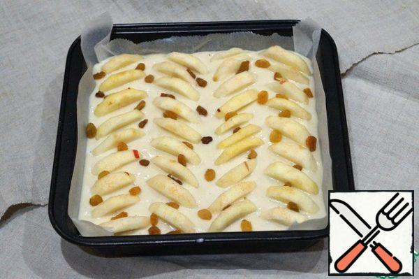 Pour the resulting egg mass into the mold. Place the peeled and sliced apples on top. Sprinkle with raisins. Bake for 30 minutes at 180 °C. Pour in 1 tablespoon of the sour cream mixture. Bake for another 7-10 minutes.