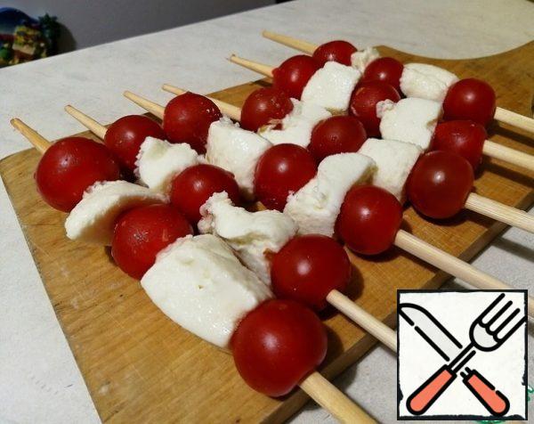 We string cherry tomatoes and mozzarella alternately on a stick (you can just take the balls, I had a little more in the store).
