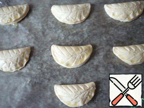Brush with beaten egg. Using a knife, carefully make a drawing of the sheet on the surface of the puff pastry, trying not to cut through it.
Put the puffs in the oven. Bake at 180 degrees for 20-25 minutes. Be guided by your technique, the ovens may differ.