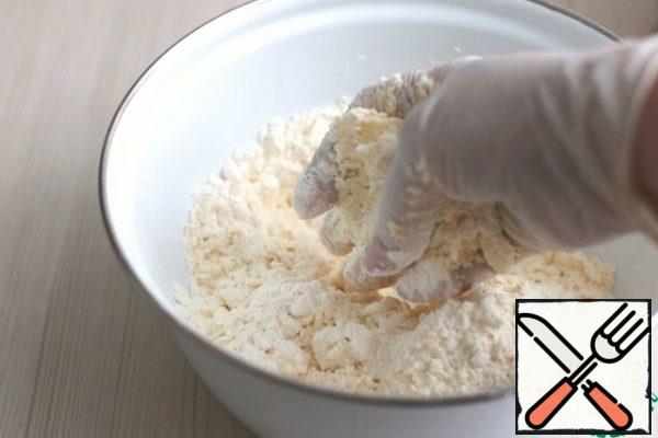 In a bowl with dry ingredients, add 100 grams of cold butter. Mix flour and butter (rub) with your hands into crumbs. Then add the sour cream mixture. Knead the dough. Wrap the dough in plastic wrap and put it in the refrigerator for 30-40 minutes.

