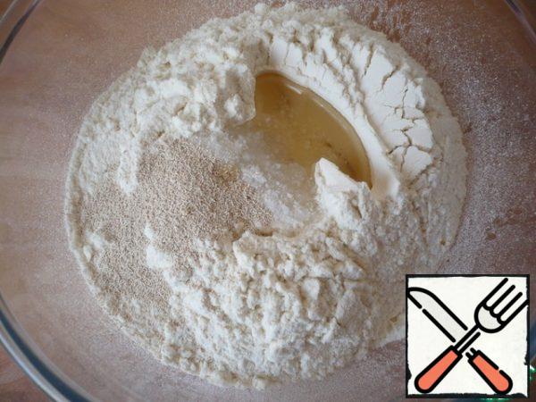 Prepare the dough. In a bowl, mix the wheat flour, salt, fast-acting yeast and vegetable oil.