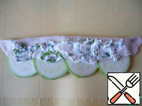 Fold the dough in half to cover 1/2 of the zucchini slices. Press both ends of the dough to secure the zucchini, and lubricate the dough with a little more garlic oil.
