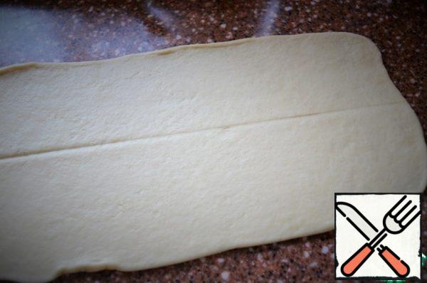Turn on the oven to warm up. Divide the dough into 3-4 parts,
roll each into a rectangle 15-17 cm wide.
Outline the middle along the entire length.
