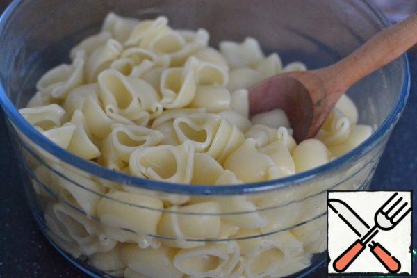 Cook pasta in salted water until tender.
Water drain, but do not pour, we will need it.
Add 1 tablespoon of sunflower oil, stir
