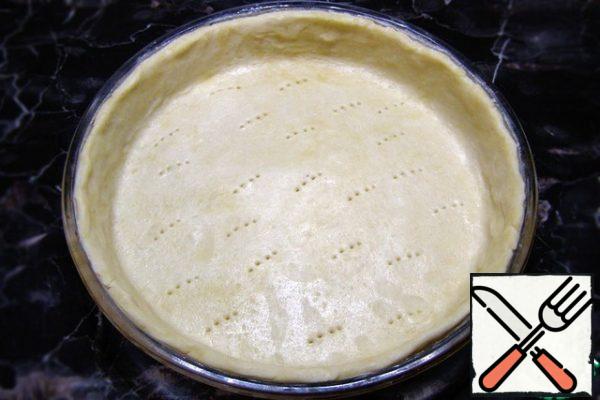 Distribute the dough in the form, closing the sides over the entire height. After that, the dough should be pricked with a fork.