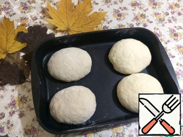 Since I don't have a bread baking dish, I put the dough on a baking sheet. It should be thick-walled so that the bread is evenly baked and does not remain raw inside. As a result, we get four buns. Cover with a kitchen towel and put in a warm place.
