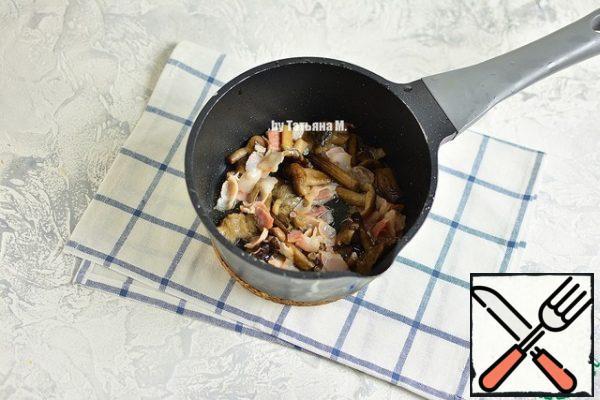 Fry in a thick-walled saucepan mushrooms with bacon on high heat.