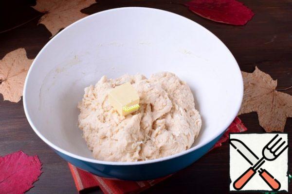 As soon as the flour is mixed with the liquid ingredients, we will add butter in portions, carefully kneading the dough after each addition of a piece of butter.
