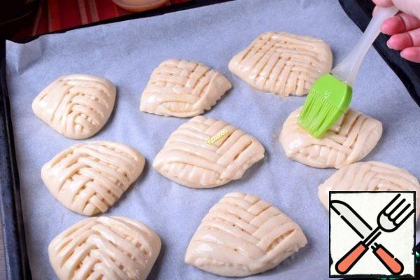 We transfer the workpiece to a baking sheet covered with baking paper, and continue to form rolls-leaves.
There is a certain distance from the workpiece. Cover the baking sheet and leave at room temperature for 20 minutes to rise. At this time, turn on the oven so that it warms up to 190-205 *C.
Lubricate the surface of the rolls with beaten egg mixed with 1 tsp of water or milk.
