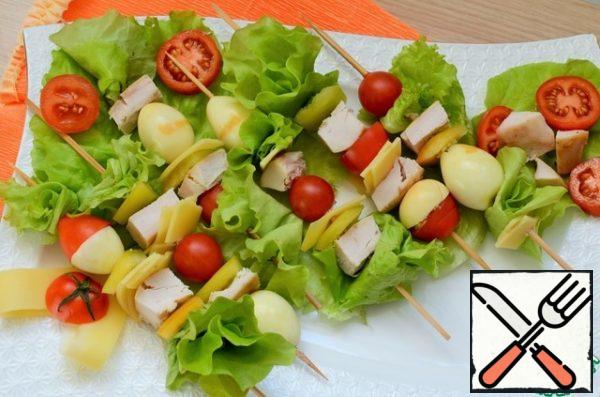 To assemble the salad, stringing products on the skewers alternately.
Put on a serving dish, garnish.