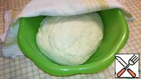 Last of all, add the sifted flour. Knead the dough, cover with a towel and put it away for an hour in a warm place.
