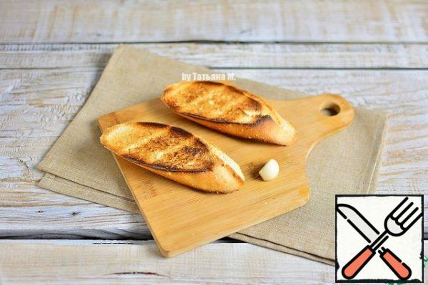 Cut the baguette into portions diagonally, fry in a toaster and rub with garlic.
