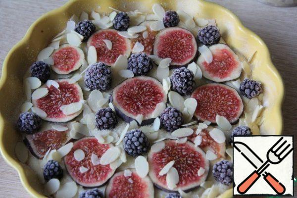 Grease the mold with oil and sprinkle with flour. Pour out the dough, put the chopped figs and blackberries. Sprinkle with sugar and almond petals.
