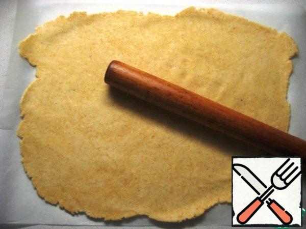 Thinly roll out the dough on a sheet of parchment.