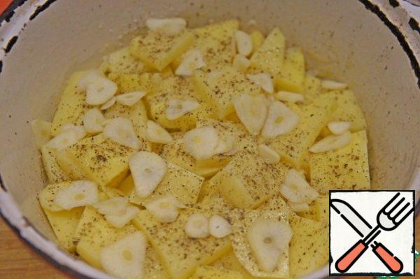 Next, put the potatoes, cut into small slices. Lightly season with salt and pepper. Sprinkle with sliced thin slices of garlic.