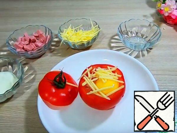 Inside the tomato add vegetable oil 1 teaspoon and coat, inside the tomato add sour cream, sausage, one egg. Sprinkle with cheese