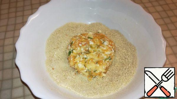 Separately, pour the breadcrumbs into a small deep plate. Take about 1 tablespoon of dough, form fluffy pancakes, roll in breadcrumbs.
