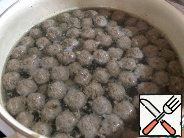 We lower our meatballs into boiling water. Very carefully remove the foam, which will be a lot. Now add the potatoes, add salt, wait until it boils. Reduce the heat and cook.
