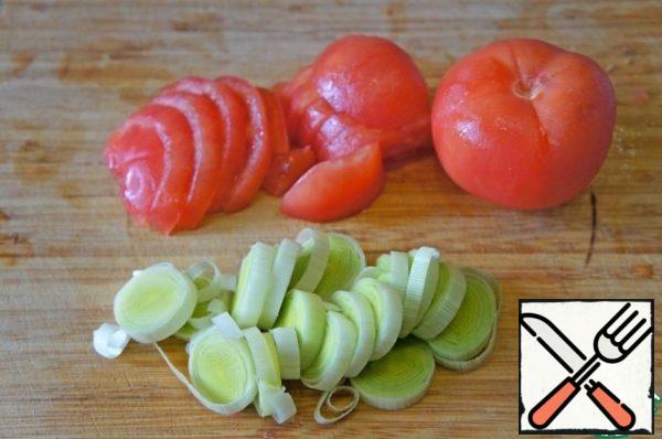 Leeks cut into rings (can be replaced with onions). Fresh tomatoes cut crosswise. Lower in boiling water for a few seconds. Then remove the skin and cut into half rings.