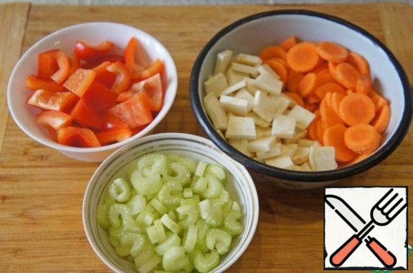 Peel the carrots and cut into rings. Bulgarian pepper cut into large squares, celery-thin slices.