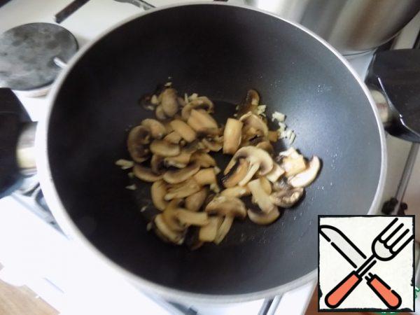 Pour the oil into the pan, heat it and spread the mushrooms. Fry them until the moisture evaporates. About a minute before readiness sprinkle mushrooms finely chopped garlic.