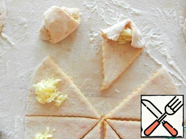 Put the cheese on a wide part of the sector. The edges of the wide part are bent to the middle, covering the filling.
