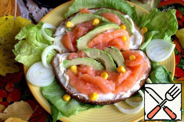 Peel the avocado and cut into thin slices. Alternate avocado with fish on bread. Finely chop the onions and serve side by side as desired.