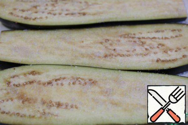 Cut off the tails of eggplants, cut lengthwise with a thickness of 3-5 mm, add salt for 30 minutes.
