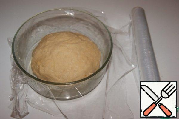 Add flour and knead a soft, slightly sticky dough to the hands. Grease a clean bowl with oil (lightly), put the dough and cover with membrane. Put in a warm place for 1 hour.