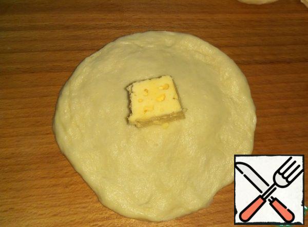Each ball of dough flatten hands, put in the middle of a piece of cheese.