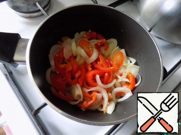 Take a frying pan, spread 20 g of butter, melt it and put the garlic, chopped finely.
After about a minute, add the onion. I cut it into half rings.
Golden and put the bell pepper. I cut it into strips. Turn down the heat and simmer for 5 minutes under the lid.