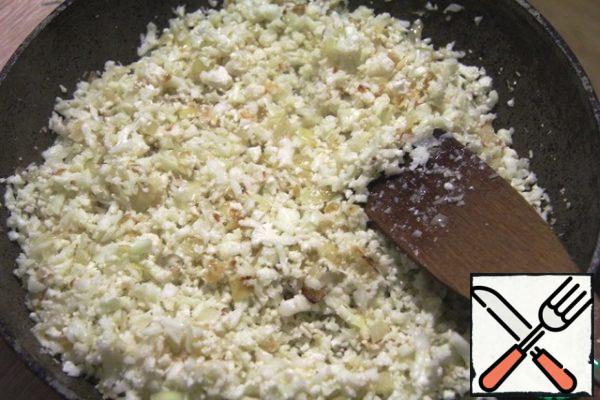 Cauliflower disassemble into small inflorescences and in a blender, pulsating mode, punch to the state of "rice". Put in the pan to the onions. Stir, add salt and simmer for about 2 minutes.