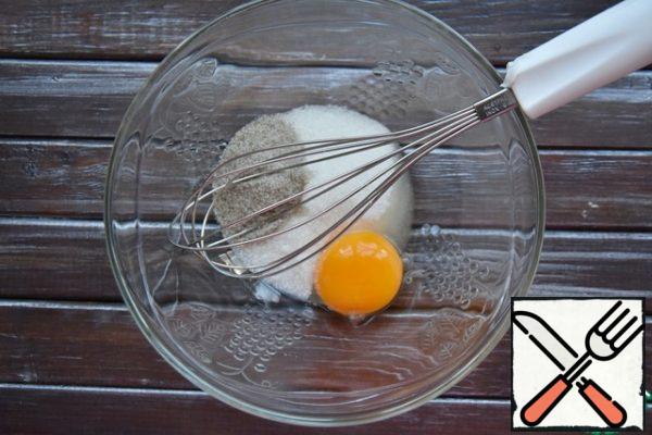 In a bowl, combine the yolk of one large chicken egg, vanilla sugar and sugar, grind the mixture with a whisk.