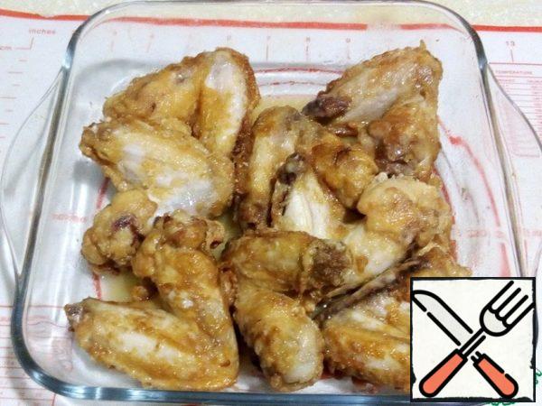 Then fry the wings lightly in a frying pan in vegetable oil, fold in a baking dish.