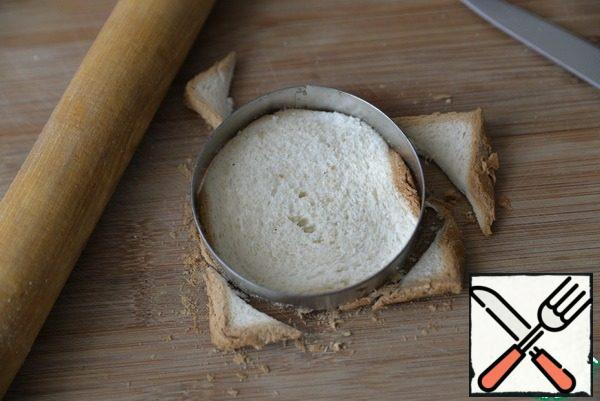Take bread for toast. If it is not quite fresh, then slightly heat in the microwave to become soft. Roll out with a rolling pin and cut out a circle.