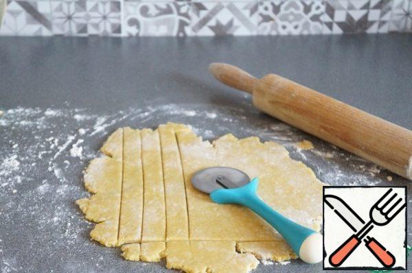 Turn on the oven. Roll out the dough about half a centimeter thick. Cut into strips.