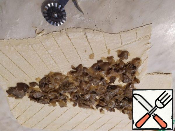 Roll out the dough into a rectangle.
We note how our Christmas tree will look, and lay out the first layer of filling - onions with mushrooms.
